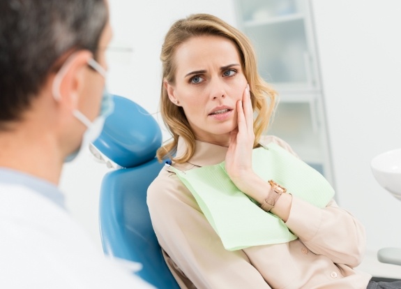 Dental patient holding her cheek in pain