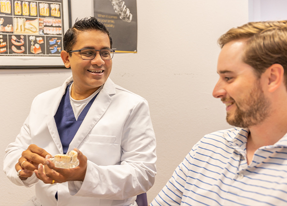 Doctor Krunal Desai showing a dental patient a model of the teeth