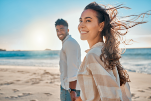 a couple smiling while visiting a beach during summertime 